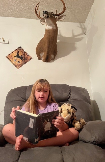 girl reading to stuffed animal