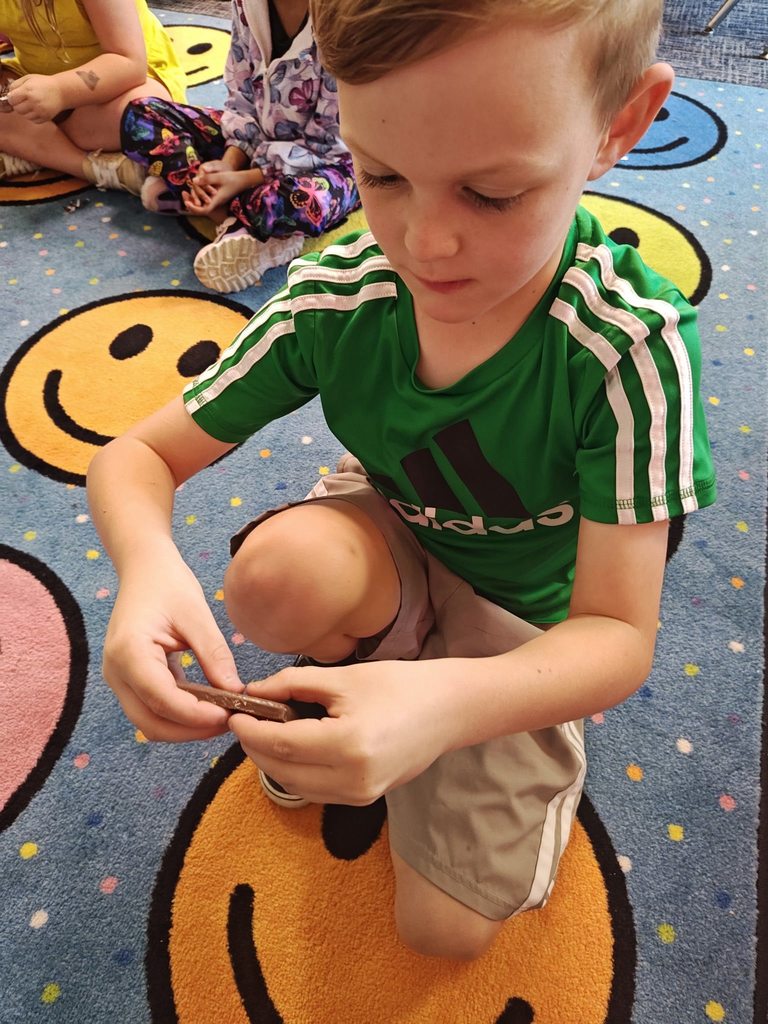 students collaborating on how to split chocolate bar. they are doing this on the rug.