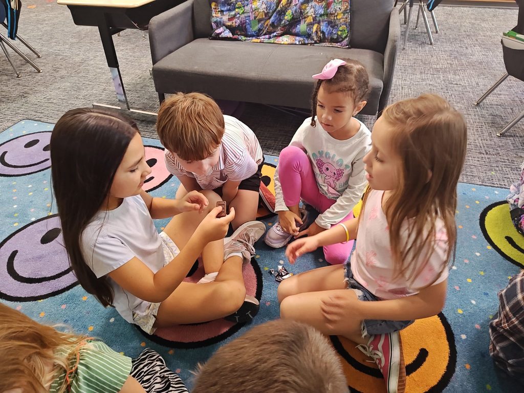 students collaborating on how to split chocolate bar. they are doing this on the rug.