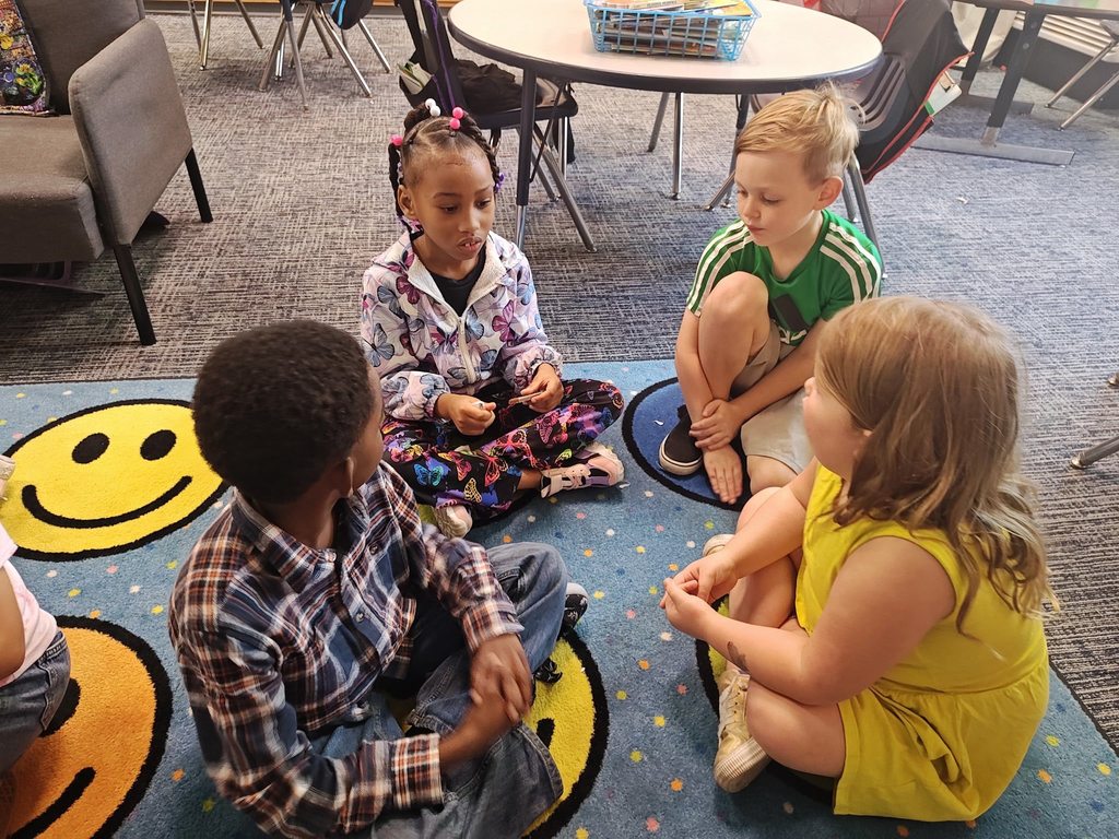 students collaborating on how to split chocolate bar. they are doing this on the rug.