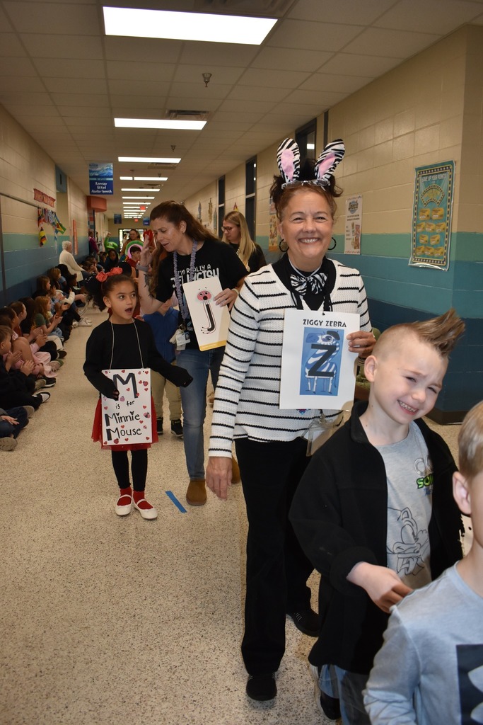 students walking in parade as many things, main teacher in photo is a zebra