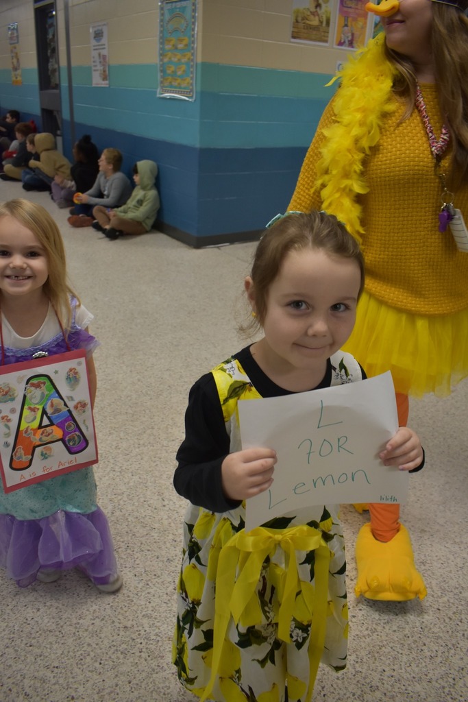 girl walking in parade representing the word lemon wearing a lemon dress