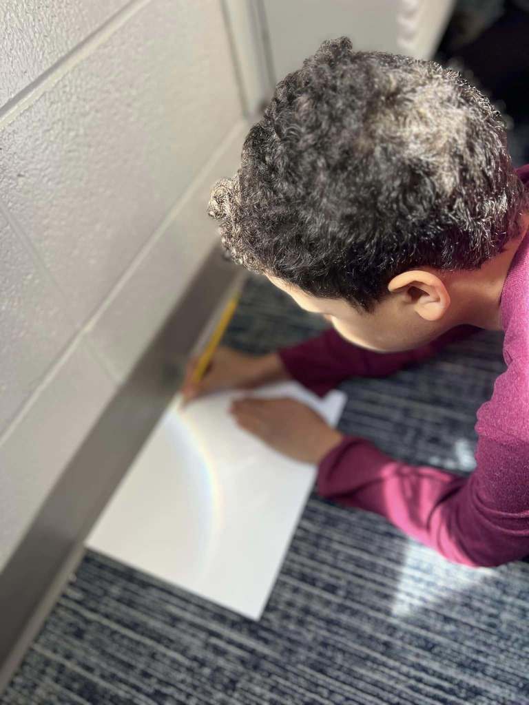 students working on project with rainbow that is coming through window
