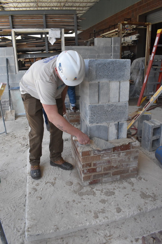 student doing grout and brick work