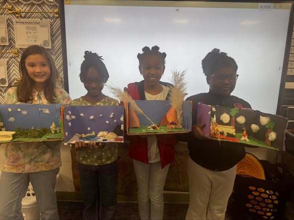 Students holding projects and smiling at camera