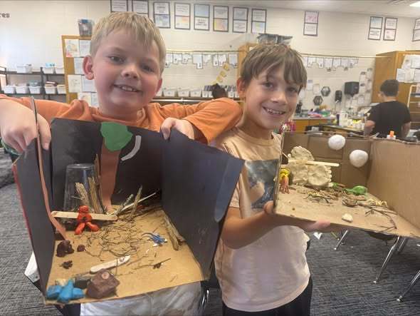 Students holding projects and smiling at camera