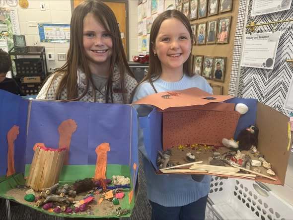 Students holding projects and smiling at camera