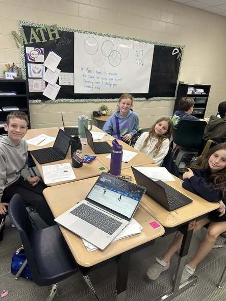 Students smiling at camera while working on assignment