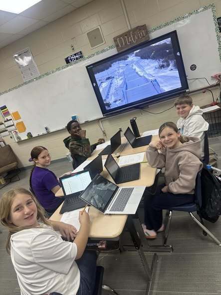 Students smiling at camera while working on assignment