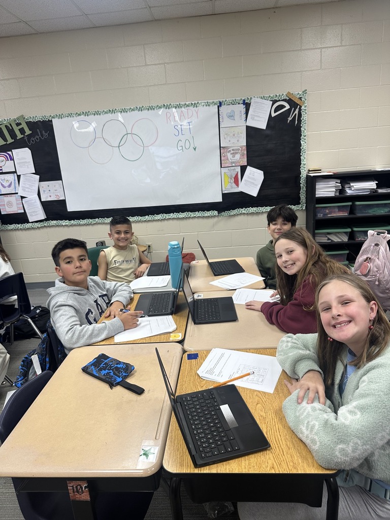 Students smiling at camera while working on assignment