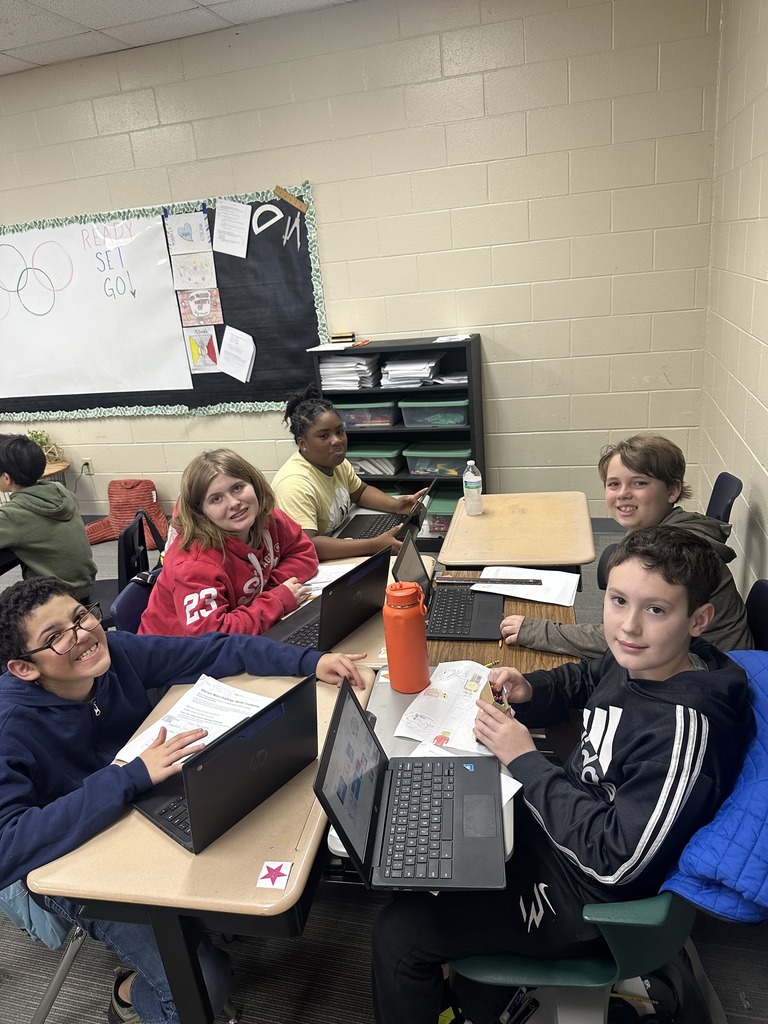 Students smiling at camera while working on assignment