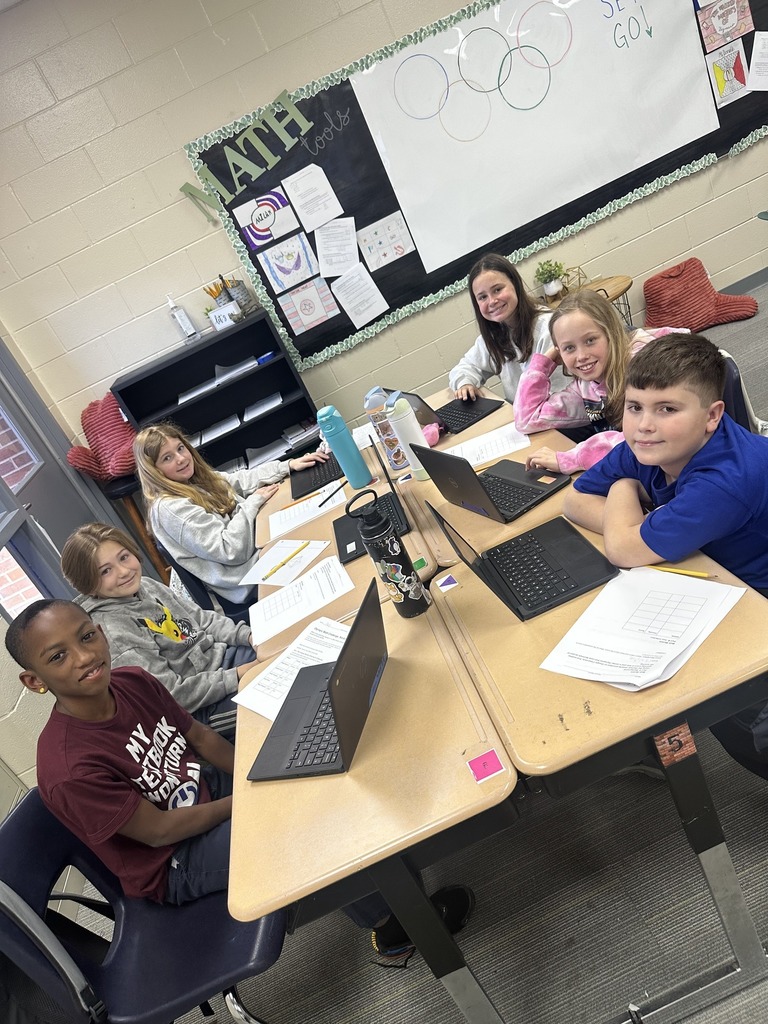 Students smiling at camera while working on assignment