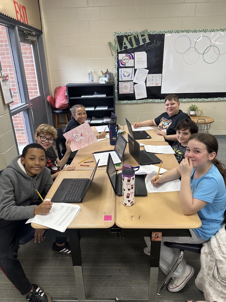Students smiling at camera while working on assignment