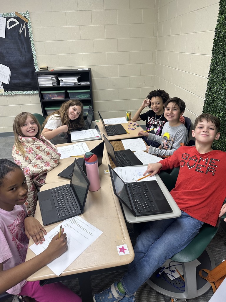 Students smiling at camera while working on assignment