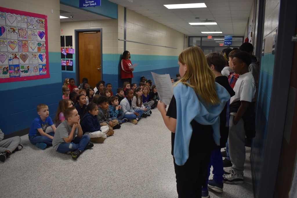 students reading poem to other students in hallway