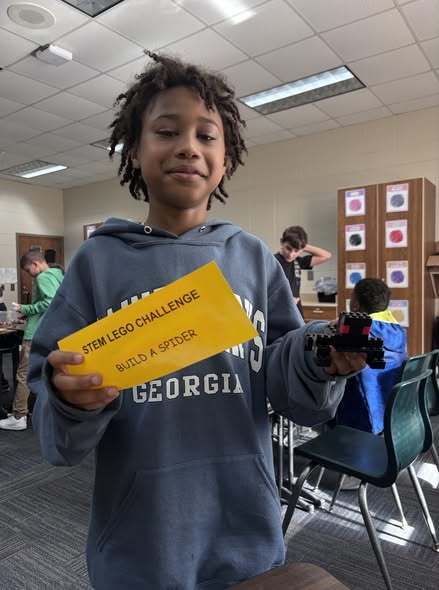 students showing their LEGO prompt and what they created