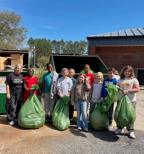 students holding bags of trash that they picked up