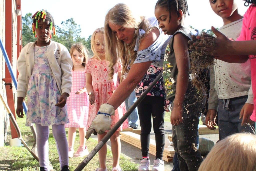 students listening to teacher while digging