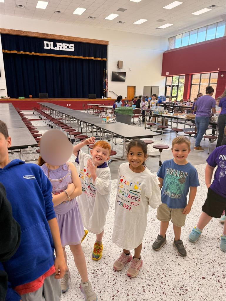 A group of elementary school students at David L. Rainer Elementary celebrate Purple Up Day. Students are wearing purple and participating in activities such as eating pizza and ice cream, getting their faces painted, and enjoying time together. The event honors military children during the Month of the Military Child.