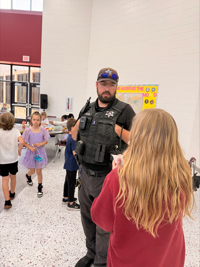 A group of elementary school students at David L. Rainer Elementary celebrate Purple Up Day. Students are wearing purple and participating in activities such as eating pizza and ice cream, getting their faces painted, and enjoying time together. The event honors military children during the Month of the Military Child.