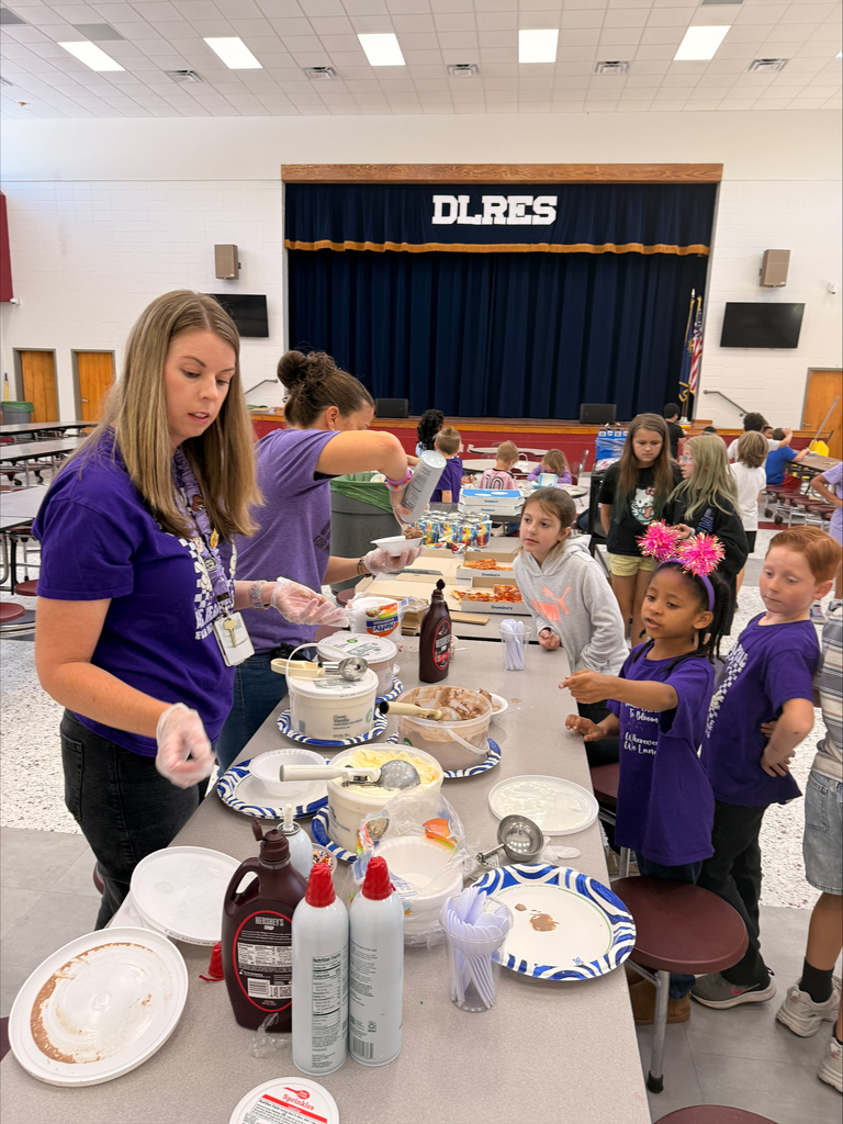 A group of elementary school students at David L. Rainer Elementary celebrate Purple Up Day. Students are wearing purple and participating in activities such as eating pizza and ice cream, getting their faces painted, and enjoying time together. The event honors military children during the Month of the Military Child.