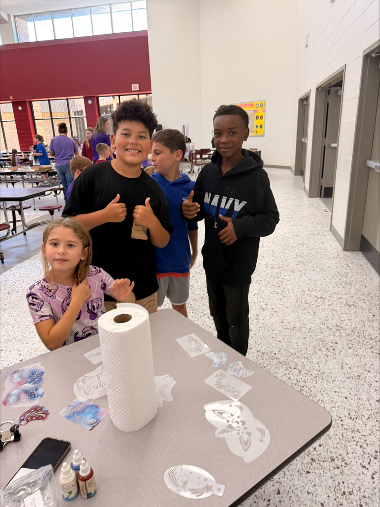 A group of elementary school students at David L. Rainer Elementary celebrate Purple Up Day. Students are wearing purple and participating in activities such as eating pizza and ice cream, getting their faces painted, and enjoying time together. The event honors military children during the Month of the Military Child.