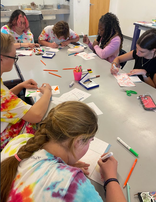 A close up of students at a table working on various art projects.