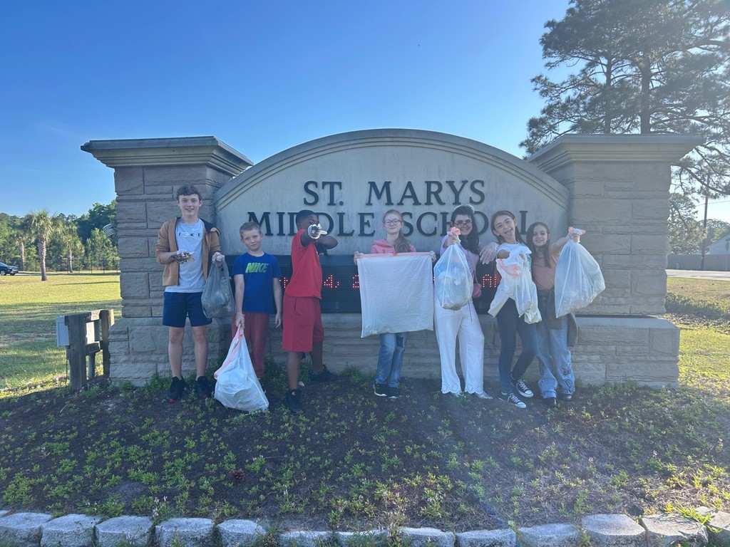 students in fornt of the SMMS sign holding their trash collected bags