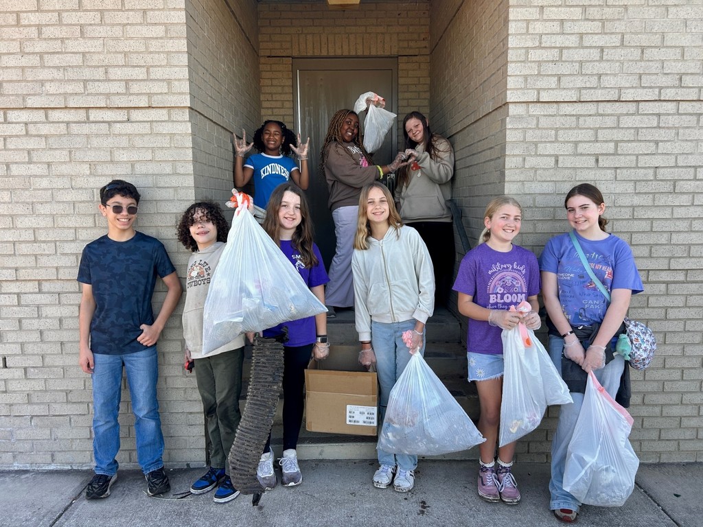 students holding up trash bags of items collected