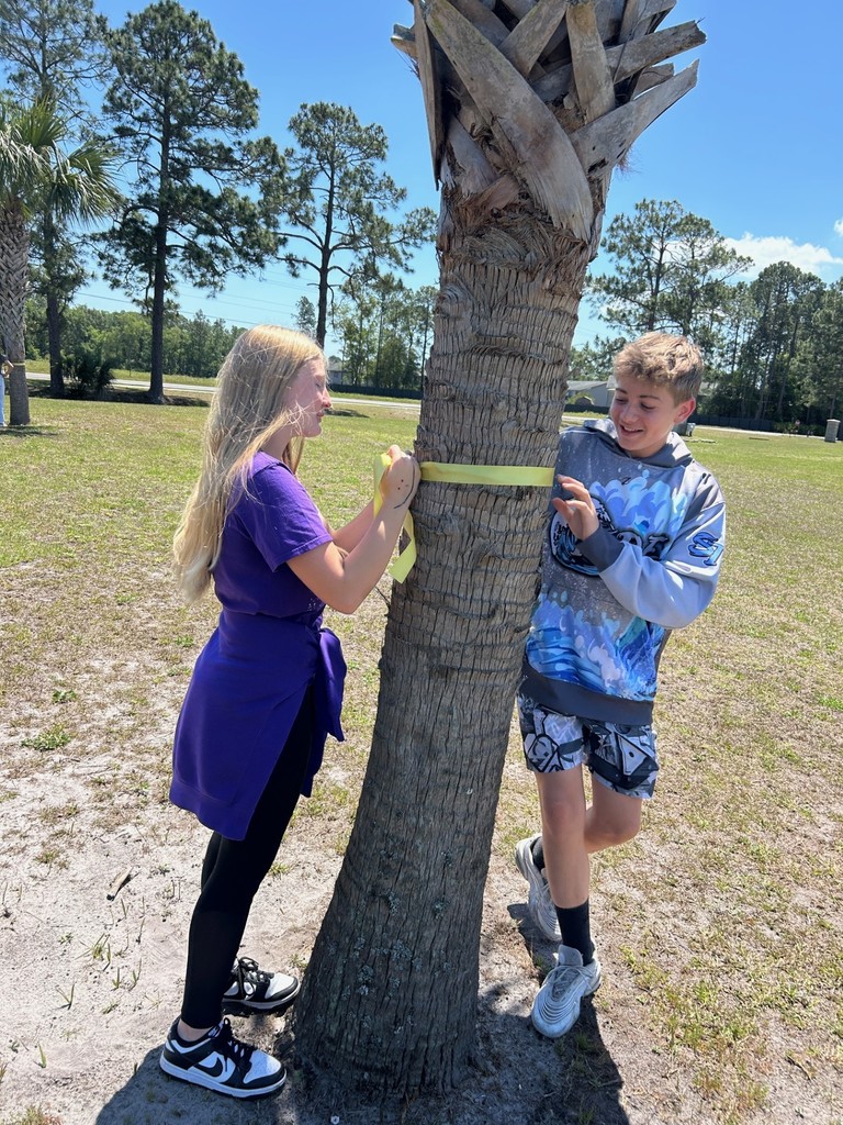 Military appreciation- students tying a yellow ribbon around a tree