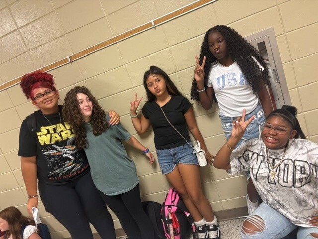 Students in the hallway on the first day of school smiling and waving.