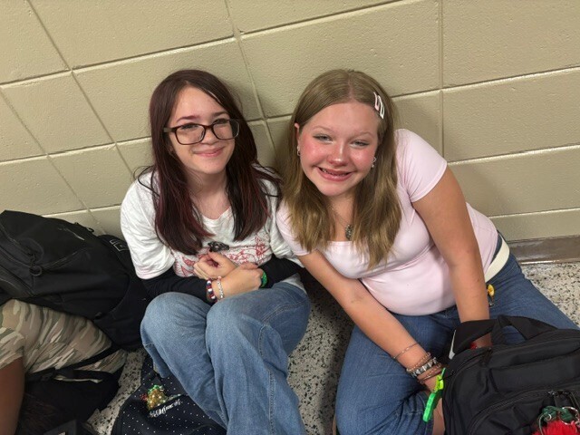 Students in the hallway on the first day of school smiling and waving.