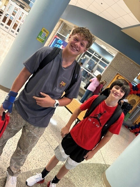 Students in the hallway on the first day of school smiling and waving.
