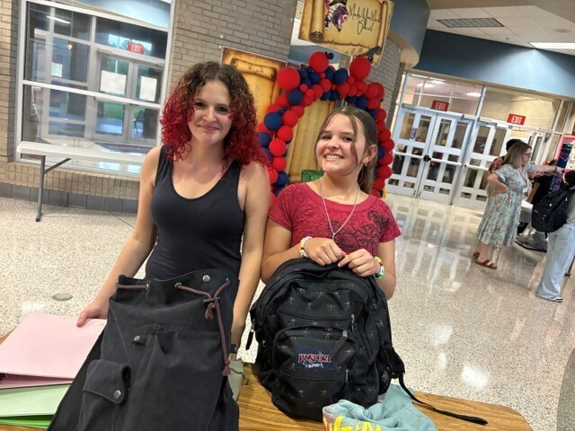 Students in the hallway on the first day of school smiling and waving.