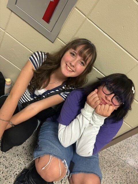 Students in the hallway on the first day of school smiling and waving.