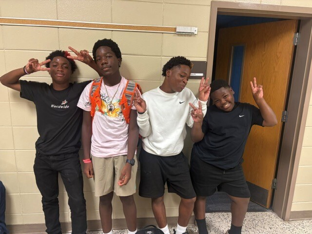 Students in the hallway on the first day of school smiling and waving.