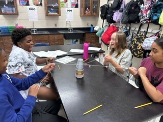 Students cooperatively working to stack cups