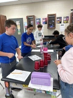 Students cooperatively working to stack cups
