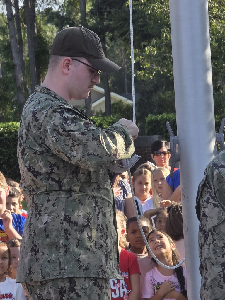 Sugarmill Elementary students partnered with local military members to honor 9/11 by singing "God Bless the U.S.A." by Lee Greenwood and clapping as the flag was raised to half-staff following a guest service member's lesson on its solemn meaning.