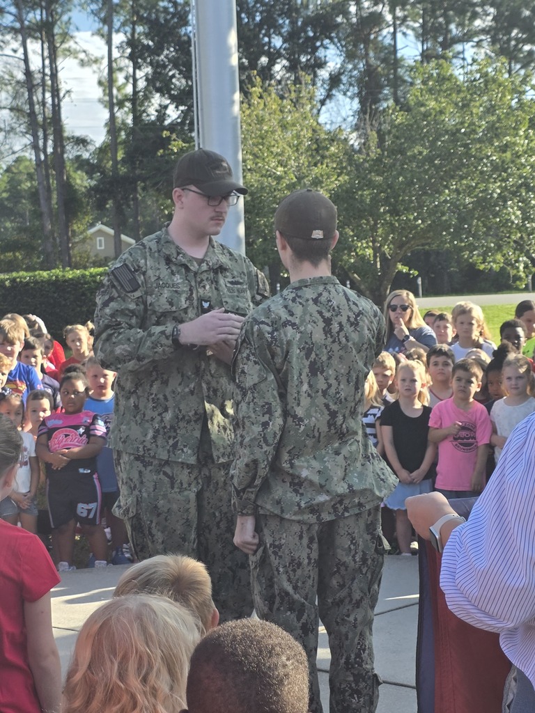 Sugarmill Elementary students partnered with local military members to honor 9/11 by singing "God Bless the U.S.A." by Lee Greenwood and clapping as the flag was raised to half-staff following a guest service member's lesson on its solemn meaning.