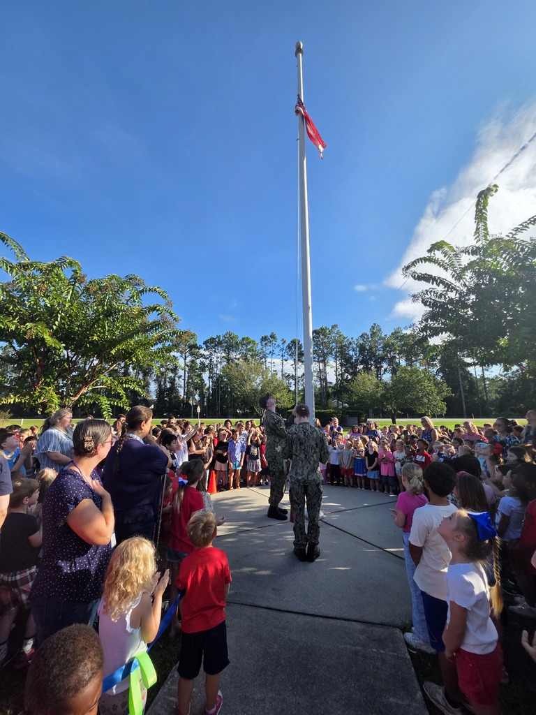 Sugarmill Elementary students partnered with local military members to honor 9/11 by singing "God Bless the U.S.A." by Lee Greenwood and clapping as the flag was raised to half-staff following a guest service member's lesson on its solemn meaning.