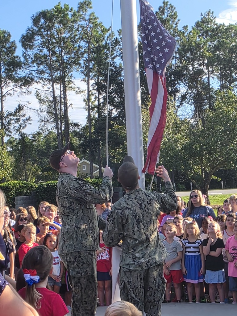Sugarmill Elementary students partnered with local military members to honor 9/11 by singing "God Bless the U.S.A." by Lee Greenwood and clapping as the flag was raised to half-staff following a guest service member's lesson on its solemn meaning.