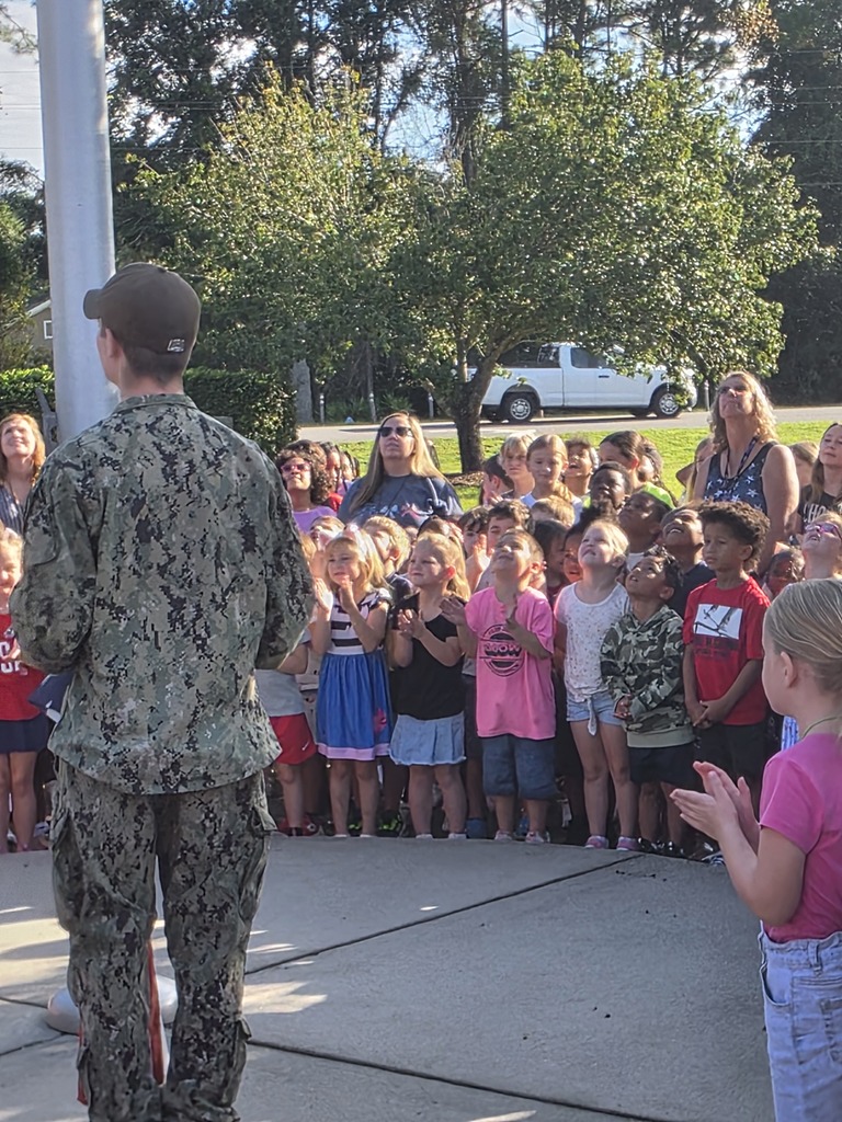 Sugarmill Elementary students partnered with local military members to honor 9/11 by singing "God Bless the U.S.A." by Lee Greenwood and clapping as the flag was raised to half-staff following a guest service member's lesson on its solemn meaning.