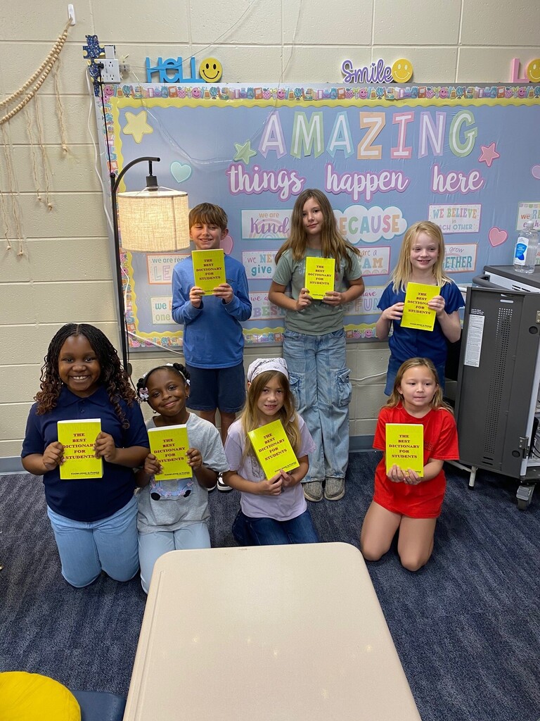 students smiling while holding up dictionaries