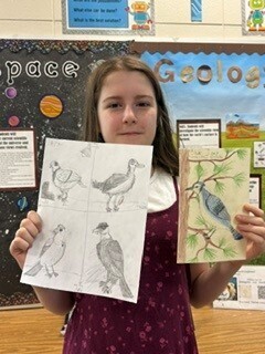 Bessette's bird club photo of student holding up artwork of their birds.
