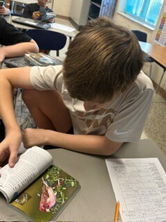 Bessette's Bird Club boy looking through a book for the project.