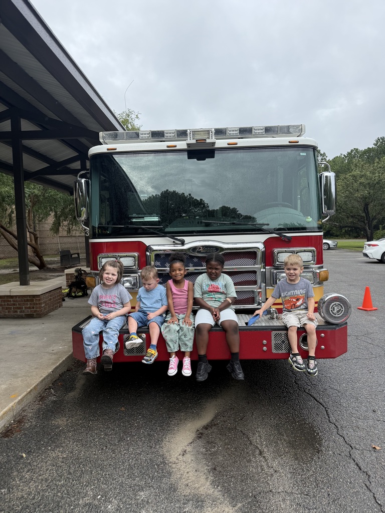 Students sitting on the front bumper of a fire truck.
