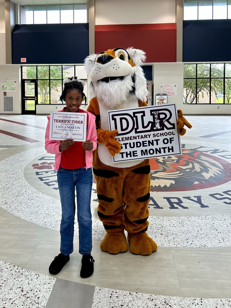 Girl standing with Tiger mascot holding a sign that says "DLR Elementary School Student of the Month"