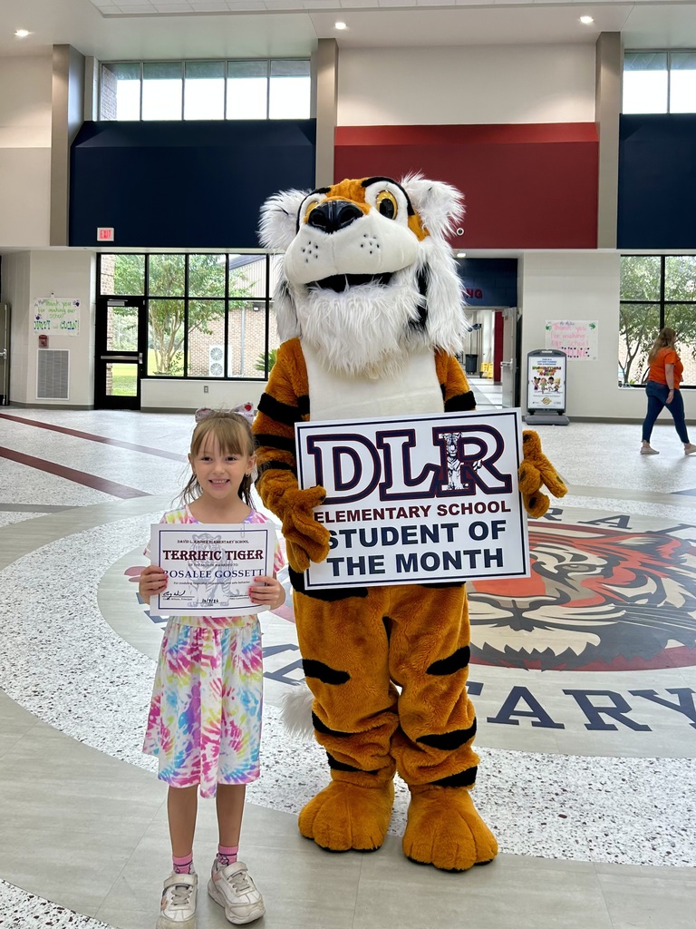Girl standing with Tiger mascot holding a sign that says "DLR Elementary School Student of the Month"