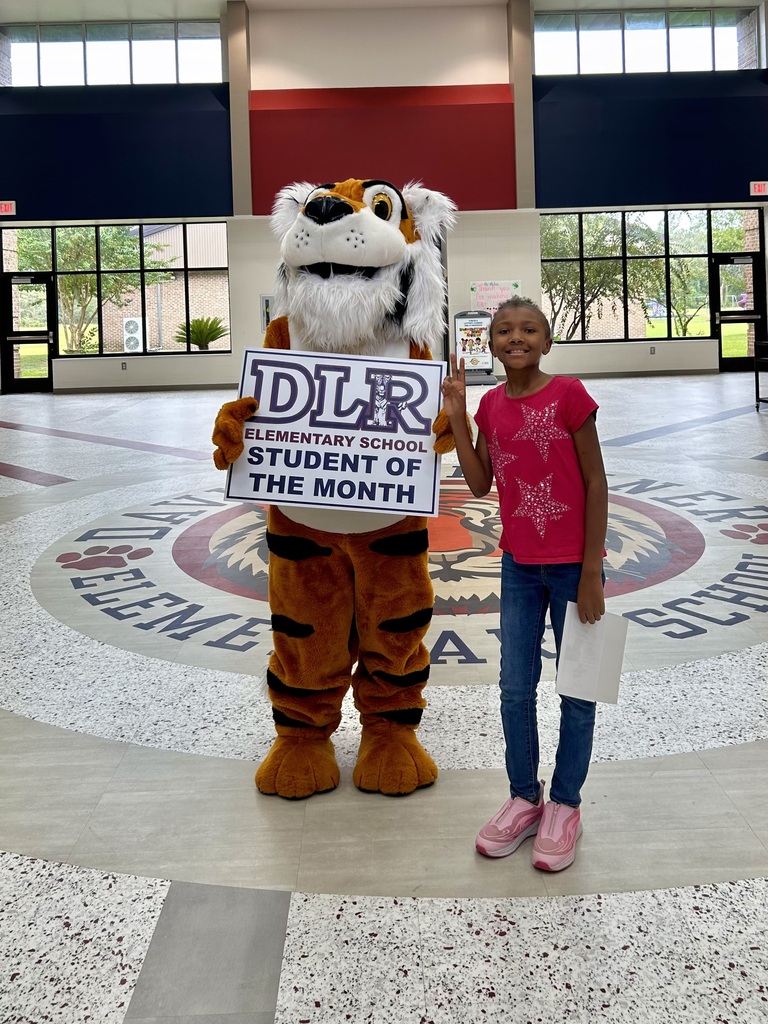 Girl standing with Tiger mascot holding a sign that says "DLR Elementary School Student of the Month"